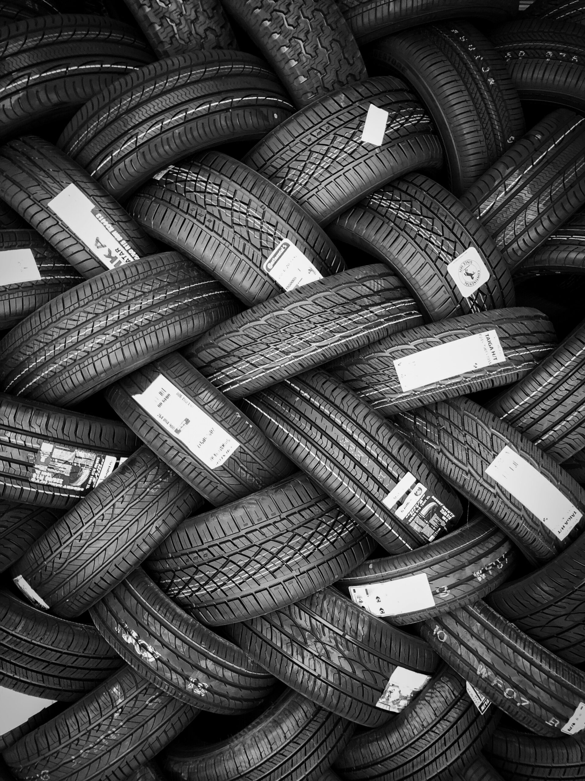 Large pile of new car tires with labels, arranged in an interwoven pattern